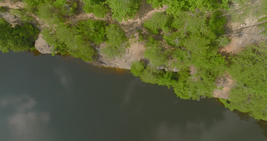 Aerial: Drone Tilt Up Shot Of Man And Woman Talking In Forest On Cliff By River - Tuscaloosa, Alabama