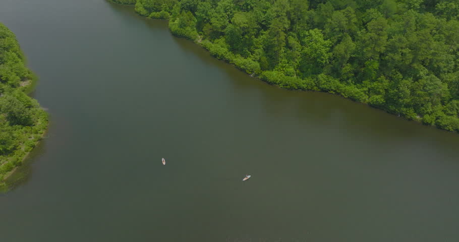 Aerial Panning Descending Shot Of Female Tourists Paddleboarding On River Amidst Forest Trees Against Clouds - Tuscaloosa, Alabama
