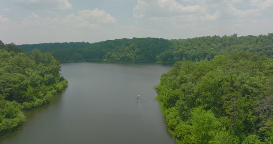 Aerial Panning Shot Of Female Tourists Paddleboarding On River In Green Forest - Tuscaloosa, Alabama