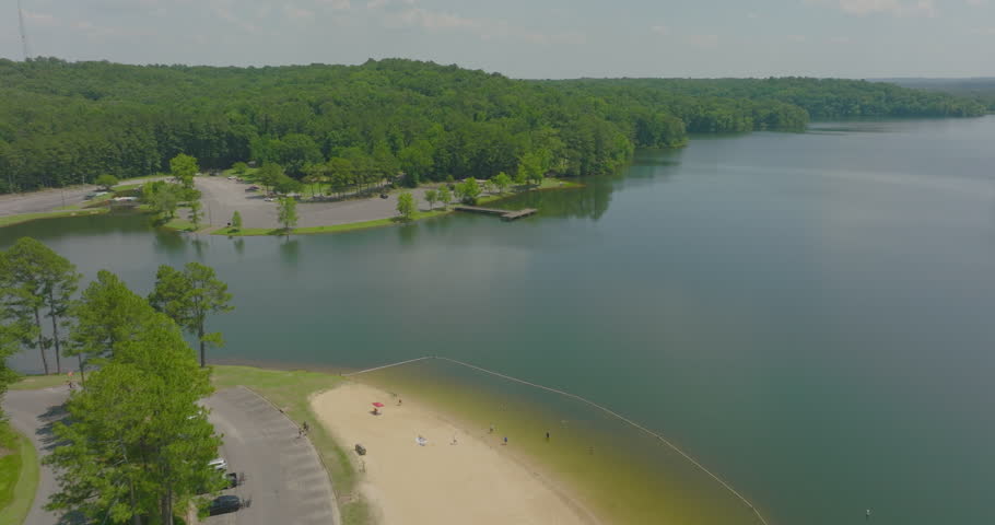 Aerial: Panning Shot Of People Playing At Beach By Riverside, Drone Descending On Sunny Day - Tuscaloosa, Alabama