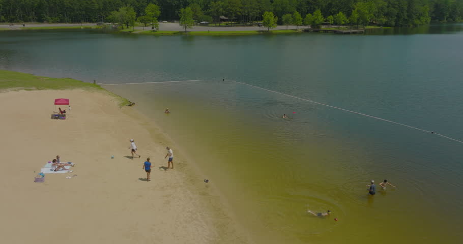 Aerial: Drone Panning Shot Of Male And Female Friends Playing At Beach On Sunny Day - Tuscaloosa, Alabama