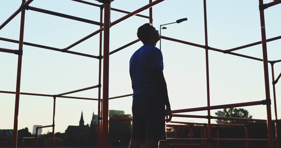 Sports Man works out at sunrise at outdoor crossfit park gym. Athlete exercises at sunset on pull-up bars, functional calisthenics training, building muscles and strength for heath and fit look.       Royalty-Free Stock Footage #1102308373