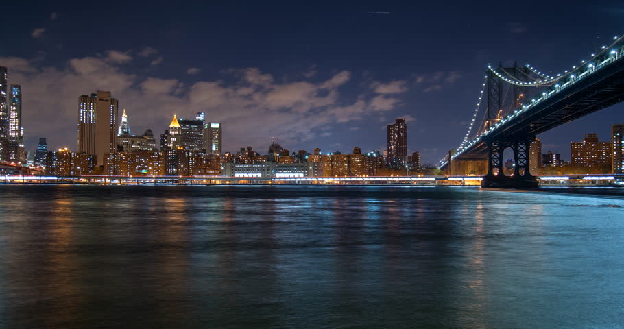 Panning Time Lapse Shot Of Illuminated Brooklyn Bridge Over East River In City At Night - New York City, New York