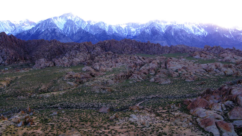 Aerial Panning Shot Of Rock Formations On A Landscape Against Snowcapped Mountains In Desert Area - Sierra County, California