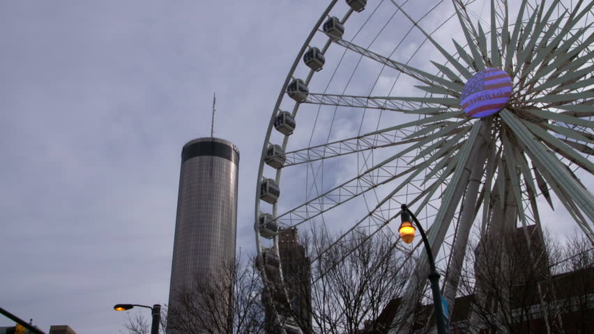 Lockdown Shot Of Popular Ferris Wheel By Skyscraper Against Sky In City - Atlanta, Georgia