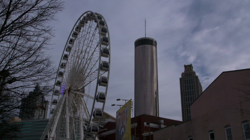 Lockdown Shot Of Famous Ferris Wheel By Tall Buildings Against Sky In Modern City - Atlanta, Georgia