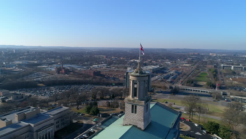 Aerial Panning Shot Of National Flags On Tennessee State Capitol In Downtown Against Clear Sky During Sunny Day - Nashville, Tennessee