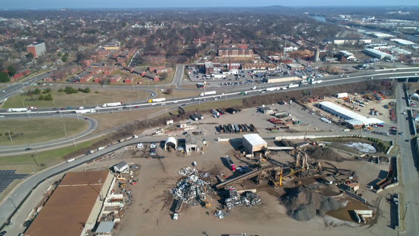 Aerial Tilt Down Shot Of Under Construction Site By Cars Moving On Road During Sunny Day - Nashville, Tennessee