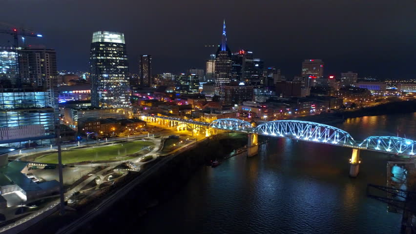 Aerial Shot Of Illuminated Famous Bridges On Cumberland River, Drone Flying Backwards In Modern City At Night - Nashville, Tennessee Royalty-Free Stock Footage #1102310435