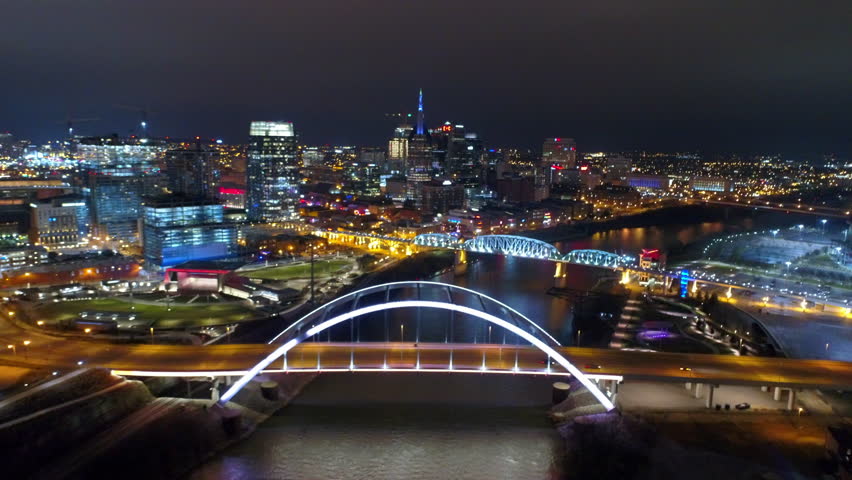 Aerial Forward Shot Of Illuminated Famous Bridges Over Cumberland River In Modern City Against Clear Sky At Night - Nashville, Tennessee Royalty-Free Stock Footage #1102310447