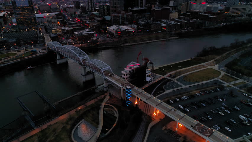 Aerial Forward Tilt Up Shot Of John Seigenthaler Pedestrian Bridge In Illuminated City - Nashville, Tennessee Royalty-Free Stock Footage #1102310531