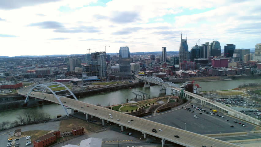 Aerial Panning Shot Of Cars Moving On Famous Bridge By Modern Buildings In Financial District Under Sky - Nashville, Tennessee