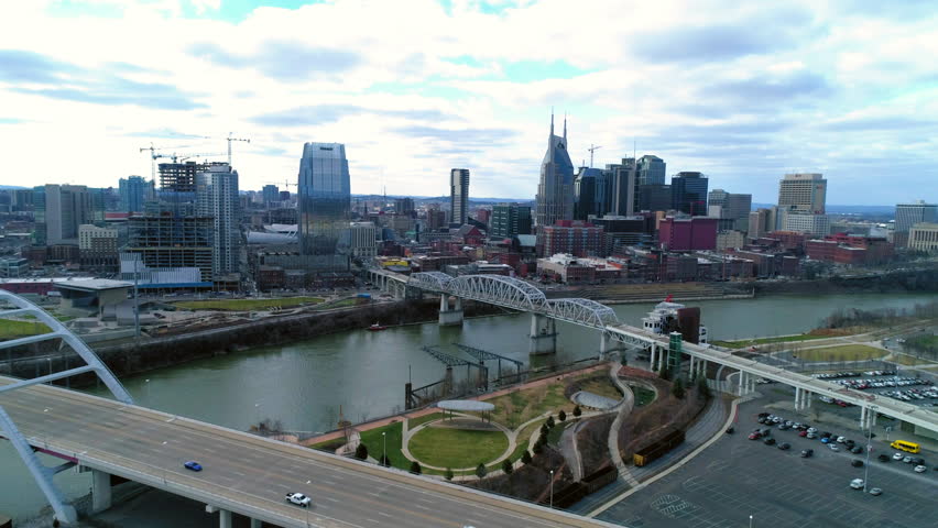 Aerial Backward Shot Of Skyscrapers By Famous Bridges With Cars In Modern City Under Cloudy Sky - Nashville, Tennessee