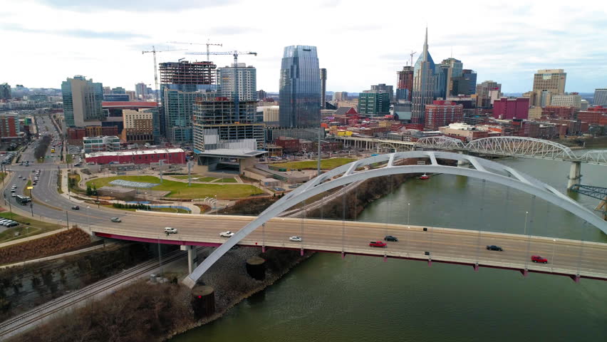 Aerial Panning Shot Of Skyscrapers By Cars Moving On Famous Bridge In Modern City Against Sky - Nashville, Tennessee