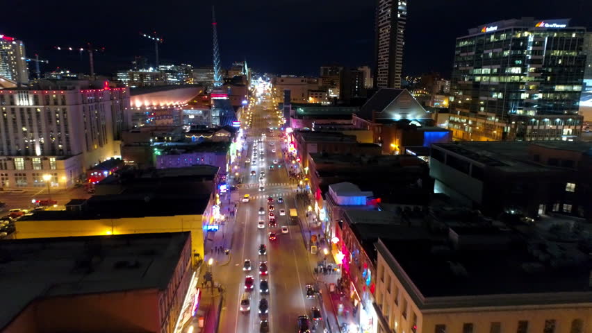 Aerial Backward Shot Of Cars Moving On Roads By Illuminated Modern Buildings In City At Night - Nashville, Tennessee