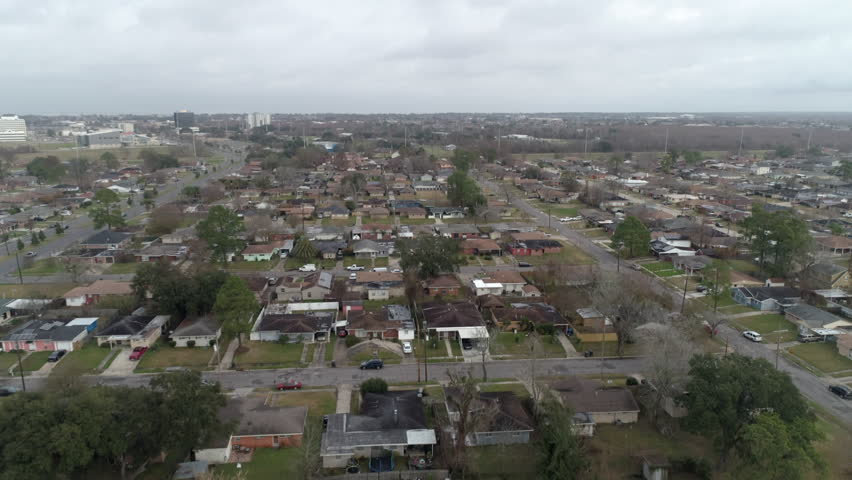 Aerial Tilt Down Shot Of Vehicles Outside Houses On City Landscape Under Cloudy Sky - New Orleans, Louisiana