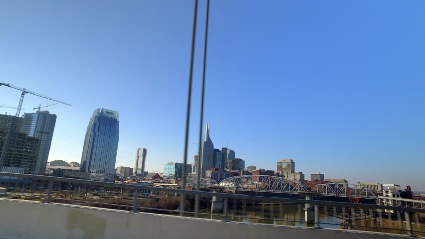 Point Of View Longest Pedestrian Bridge By Office Buildings In Downtown Seen From Moving Vehicle On Sunny Day - Nashville, Tennessee Royalty-Free Stock Footage #1102311257