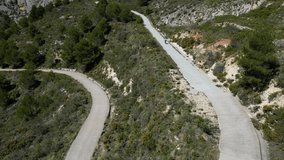 Drone flying high over a female cyclist.Female professional cyclist is training on a gravel bike.Sport cycling motivation drone video.Gravel cycling adventure.Riding the spanish gravel mountains roads