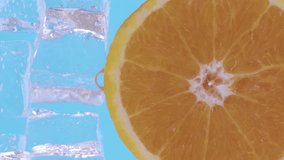 Water drips flowing from a sliced sweet and fresh orange down on a blue background, fruit for frash and natural juice, cold diet drink with vitamin c. Slow motion, filmed on cinema camera, 4K.