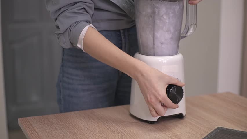 a woman in a shirt turned on the blender, turned the toggle switch. slow motion video. High quality Full HD video recording
