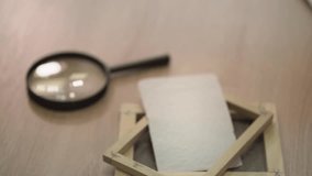 a paper press, ready-made paper samples and a large magnifying glass lie on the table. slow motion video. close-up. High-quality FullHD video recording