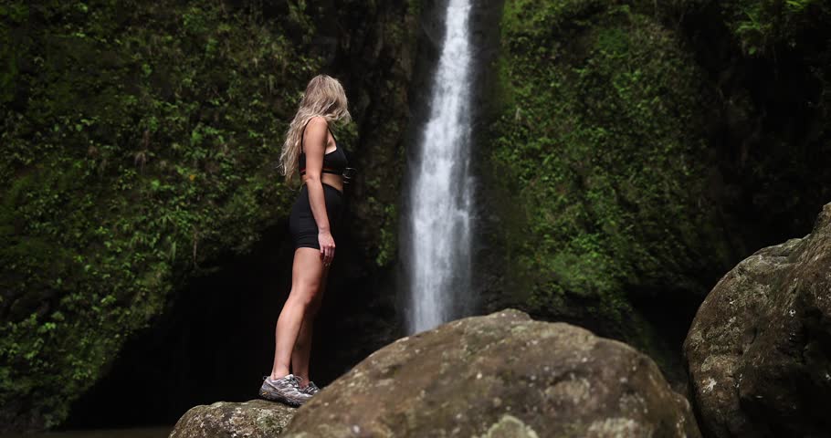 Girl hiker in front of waterfall in hawaii green jungle forest.  Royalty-Free Stock Footage #1102323827