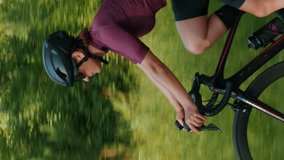 Woman athlete training on bicycle. Vertical video. Female pro cyclist riding road bike outdoors, preparing for competition bike race. Professional triathlete cycling in sunlights. Cycling concept