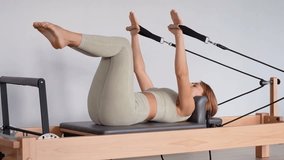 Woman training pilates on the reformer bed. Reformer pilates studio machine for fitness workouts in gym. Fit, healthy and strong authentical body. Fitness concept - Powered by Shutterstock - Get 15% off with code: PIKWIZARD15