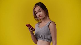 4k video of one girl who reacts emotionally to a message on her phone over yellow background.