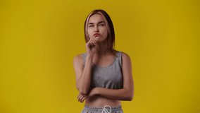 4k video of one girl which planning something and when an idea came up she is pointing up over yellow background.