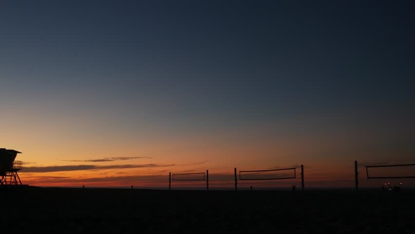 Volleyball net silhouette on beach court at sunset, California coast, USA. Sport field for volley ball game. Twilight sky background, sundown on Mission beach, San Diego, ocean shore near Los Angeles.