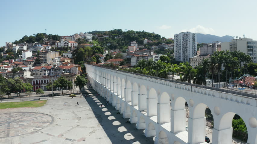Aerial view of Carioca Aqueduct and train riding on the top against panorama of Santa Teresa buildings on the hill, Rio de Janeiro Royalty-Free Stock Footage #1102338553