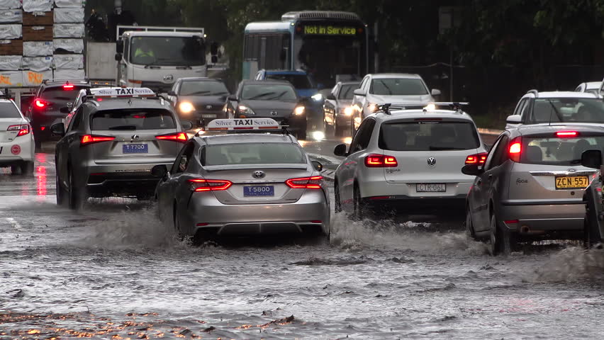 A row of cars passing through a road flooded by heavy rain Royalty-Free Stock Footage #1102340549