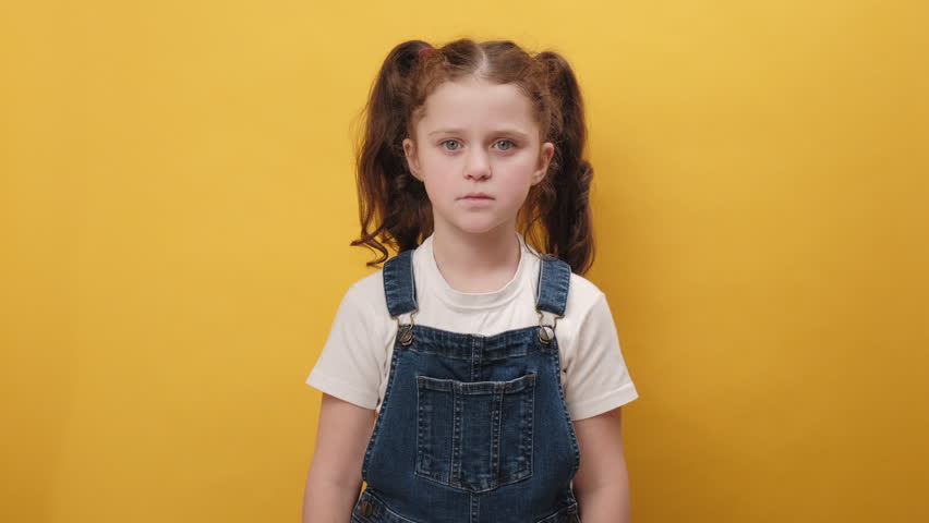 Portrait of little girl kid wearing casual clothes smelling something stinky and disgusting, intolerable smell, holding breath with fingers on nose, isolated on yellow background. Bad smell concept Royalty-Free Stock Footage #1102341057