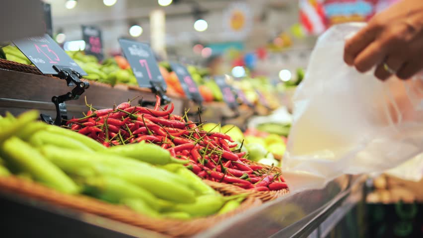 Young Woman Puts Red Hot Thai Chilli Peppers in Plastic Bag at Veggies Section in Grocery Store, High Quality 4K Consumerism Shopping Concept, Thailand. Royalty-Free Stock Footage #1102347595