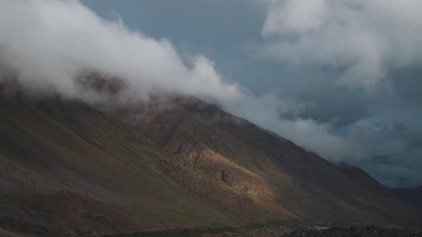 Clouds above the snowy mountain peaks during the sunset at Darcha in Lahaul Spiti district, Himachal Pradesh, India. Clouds cover the snowy mountain peaks during the snowstorm in mountains.