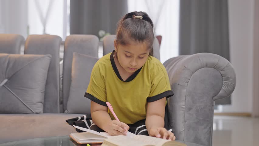 Serious Indian kid girl studying at home