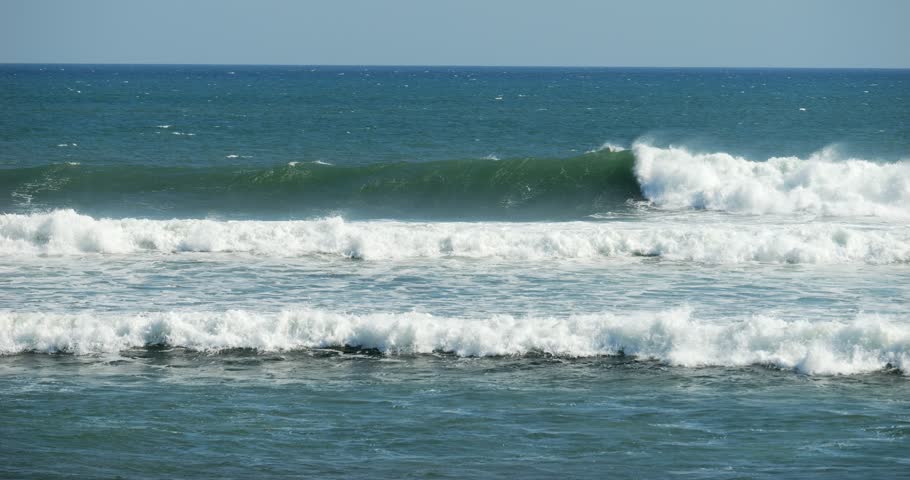 Beautiful ocean waves roll and turn into a white bubbling breaker, slow motion footage from the shore. Unsuitable for surfing, but showing power of nature, sea near Canggu beach, Bali Island