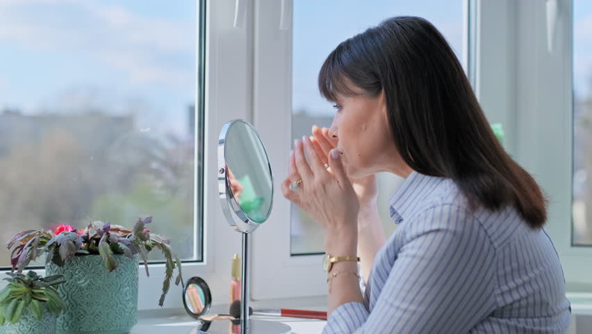 Happy middle aged woman touching her face, admiring herself in mirror Royalty-Free Stock Footage #1102355471
