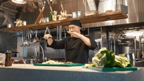 Portrait of cheerful young asian professional chef chopping vegetables on cutting board with knife performing japanese ritual playing around enjoying work. Looking at camera smiling. - Powered by Shutterstock - Get 15% off with code: PIKWIZARD15