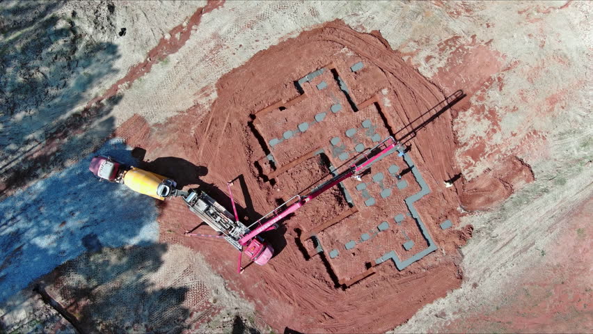 Construction worker is pouring cement concrete by using an automatic pump to lay foundation for building
