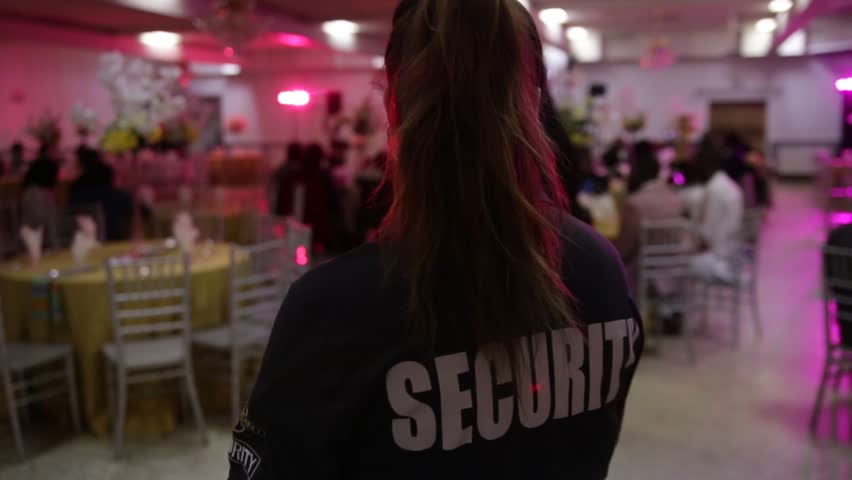 A female security guard is protecting an entrance of a private event.  Royalty-Free Stock Footage #1102362927