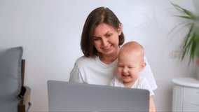 Mom and little daughter are studying at the computer. The laptop is on the table and Mom is teaching her daughter how to use the computer. People in white shirts against the background of white walls