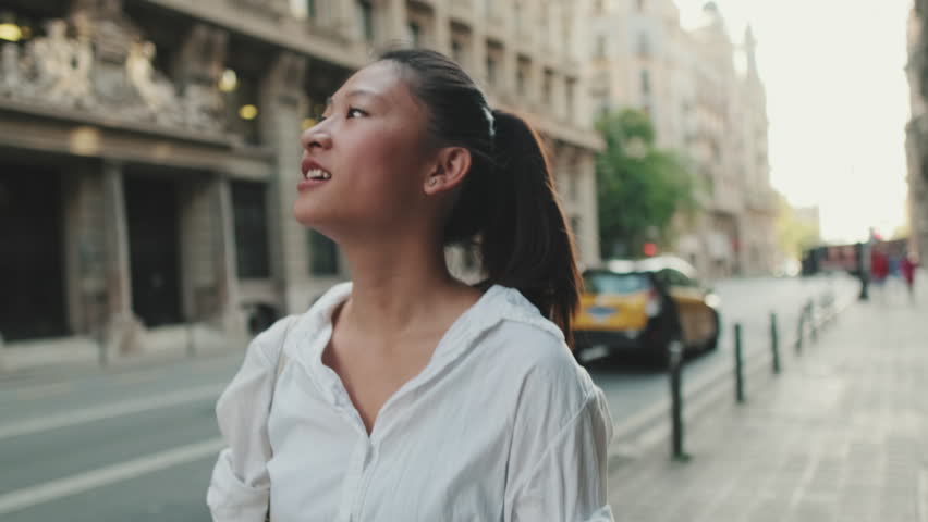 Young woman walks down the street and looks around