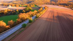 Flying over nice road during beautiful sunset. Aerial view on autumn coloured countryside