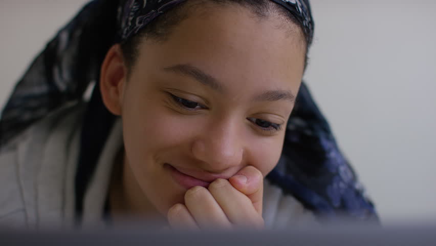 Young girl on her digital tablet reacts with laughter at something on her screen