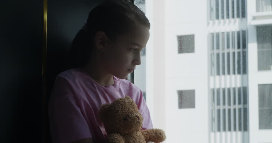 Cute little girl portrait child is sad in her room with a toy in her hands, child in depression in the room with a toy bear in his hands. Sad family. Fear of child in dark. Family violence concept | Shutterstock HD Video #1102369969