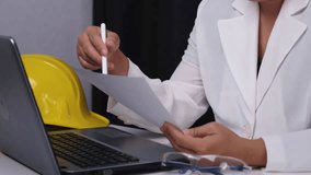 Portrait of female engineer sitting at desk using laptop computer in office, analyzing data in documents. - Powered by Shutterstock - Get 15% off with code: PIKWIZARD15