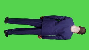 Vertical video: Back view of injured businessman wearing suit and cervical neck collar standing over full body green screen. Young man employee being in pain after injury, medical brace for fracture
