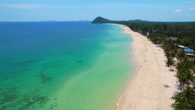 The sandy beach and coconut tree-lined stretches out for miles in Thailand is a picturesque scene of natural beauty. The beach is located along the coastline. Travel and nature concept. 4K Drone
